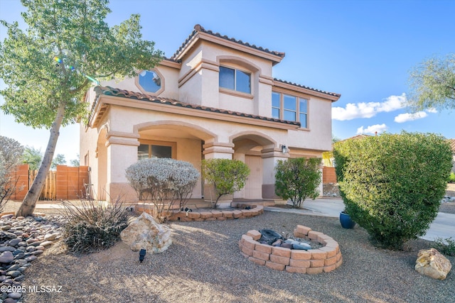 mediterranean / spanish-style house with covered porch, fence, and stucco siding