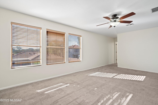 spare room with ceiling fan, visible vents, and baseboards