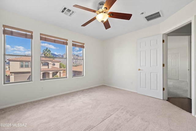 carpeted empty room featuring ceiling fan, visible vents, and baseboards