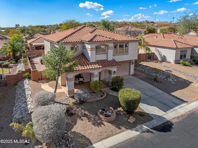 mediterranean / spanish house with a garage, concrete driveway, fence, and stucco siding