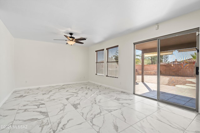 unfurnished room with ceiling fan, marble finish floor, and baseboards