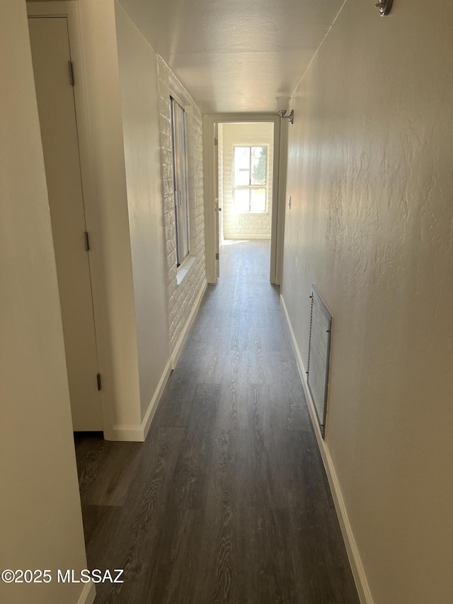 corridor featuring visible vents, baseboards, and wood finished floors