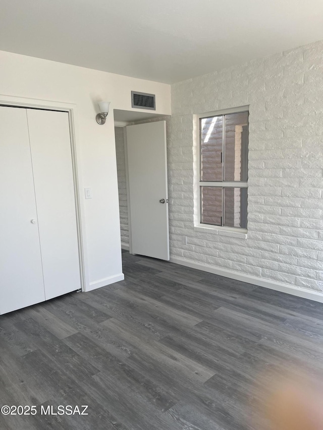 exterior space featuring visible vents, brick wall, baseboards, wood finished floors, and a closet