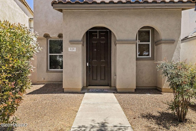 entrance to property with stucco siding and a tile roof