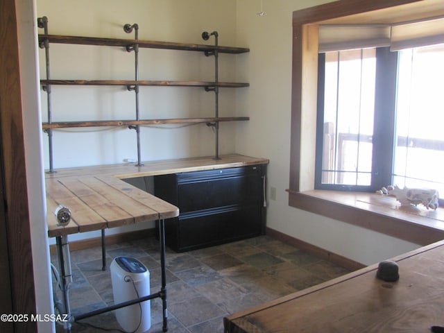 interior space with a healthy amount of sunlight, baseboards, and stone finish flooring