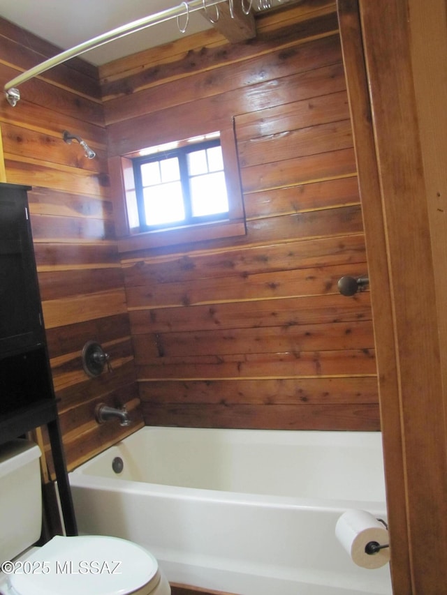 full bathroom featuring wooden walls, toilet, and bathtub / shower combination