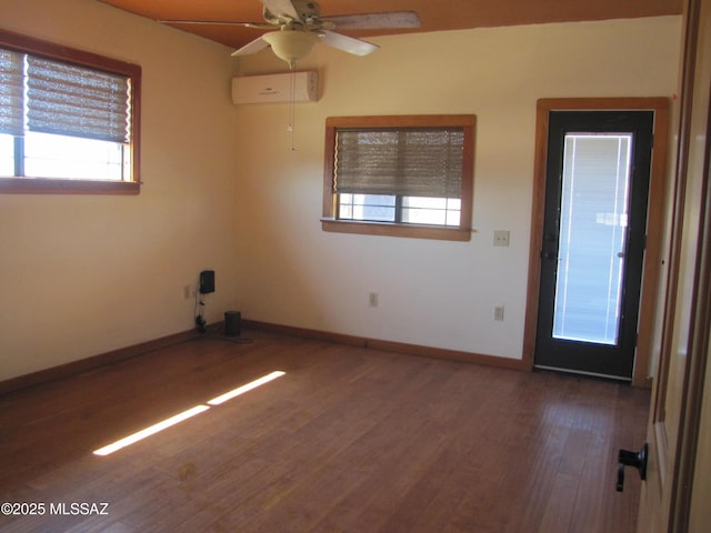 spare room with ceiling fan, wood finished floors, baseboards, and a wall mounted AC