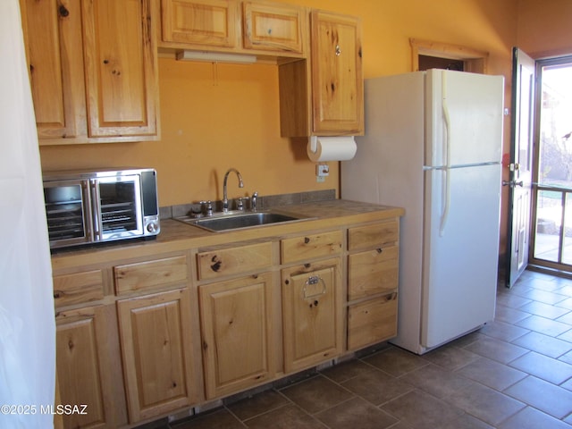 kitchen featuring a sink, a healthy amount of sunlight, light brown cabinetry, and freestanding refrigerator