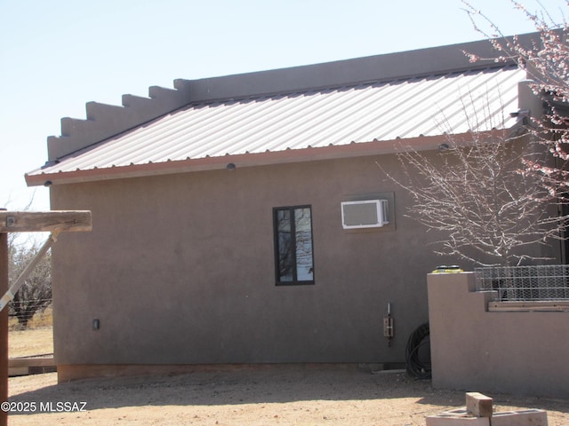 view of property exterior featuring stucco siding, a wall mounted air conditioner, and metal roof
