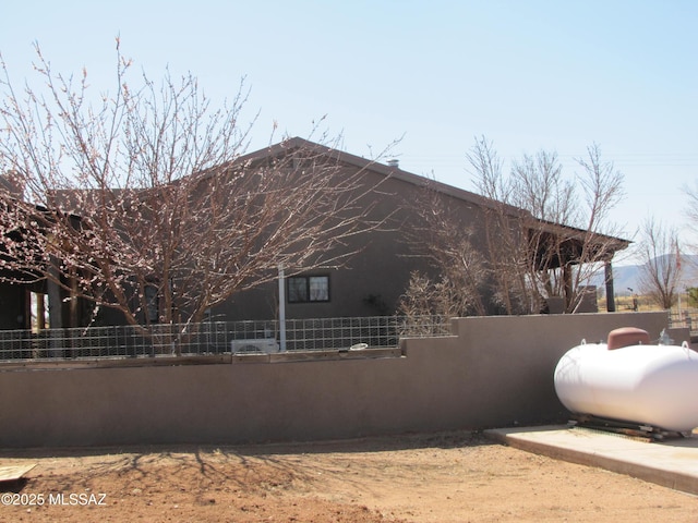 view of side of property with stucco siding and fence