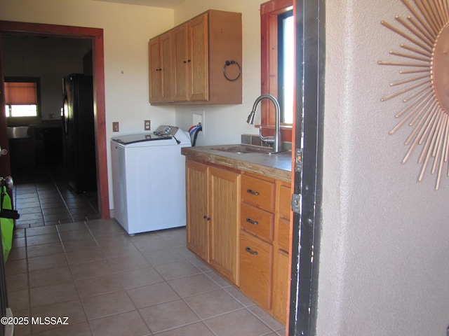 kitchen featuring a sink, washer / clothes dryer, freestanding refrigerator, and light tile patterned floors