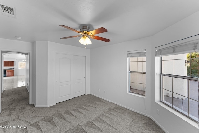 unfurnished bedroom featuring visible vents, a closet, carpet floors, baseboards, and ceiling fan