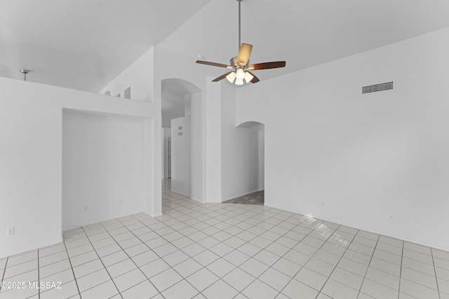 unfurnished room with arched walkways, high vaulted ceiling, light tile patterned flooring, and a ceiling fan