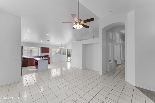 living room with light tile patterned floors, recessed lighting, ceiling fan with notable chandelier, and arched walkways