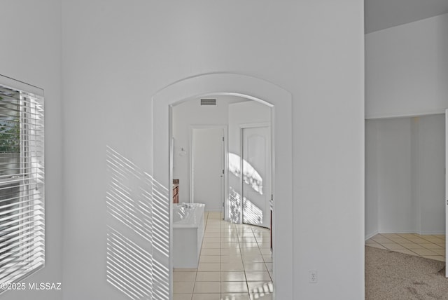 corridor with light tile patterned floors, visible vents, and arched walkways