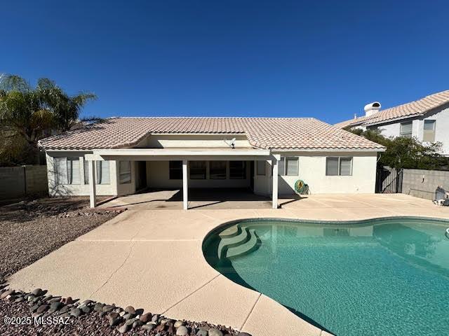 rear view of house featuring a tiled roof, fence, a fenced in pool, and a patio area