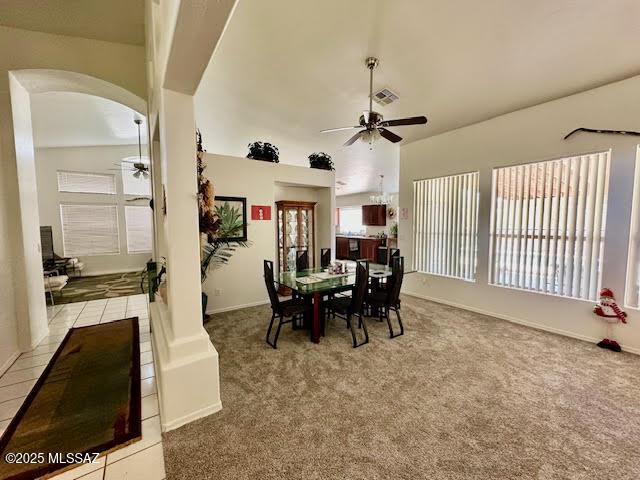 carpeted dining area featuring visible vents, arched walkways, and a ceiling fan