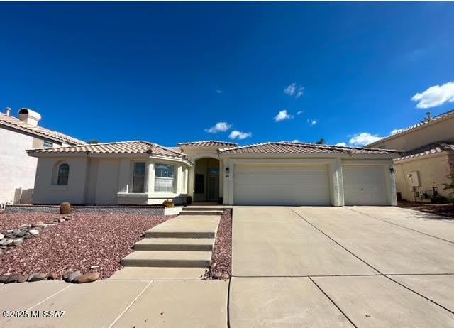 view of front of house with a tile roof, a garage, driveway, and stucco siding