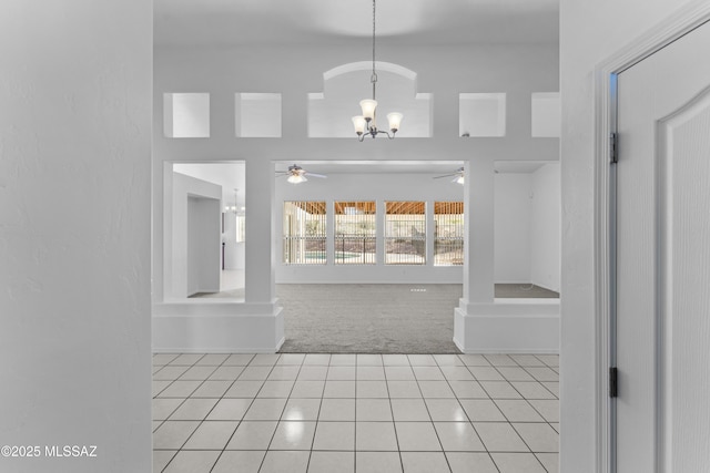 entrance foyer with light tile patterned flooring, ceiling fan with notable chandelier, and light carpet