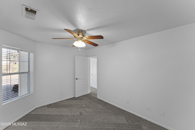 carpeted spare room featuring visible vents, baseboards, and ceiling fan