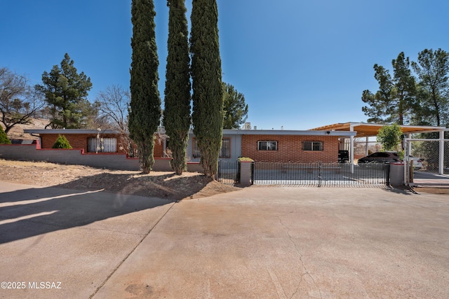 ranch-style home featuring a fenced front yard, an attached carport, driveway, and a gate