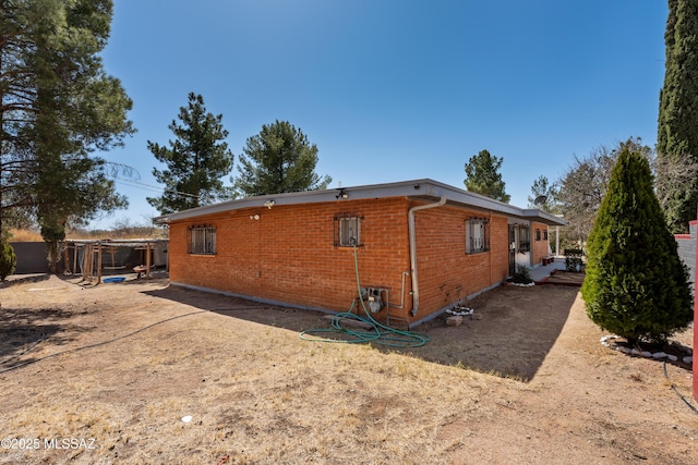 rear view of property featuring brick siding and fence