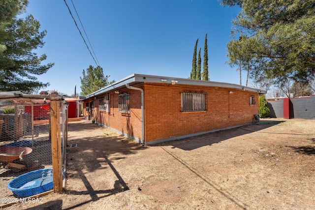 view of property exterior with brick siding and an outdoor structure