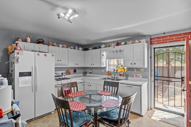 kitchen with a sink, under cabinet range hood, white appliances, light countertops, and light floors