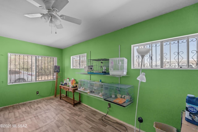 interior space with baseboards, wood finished floors, and a ceiling fan