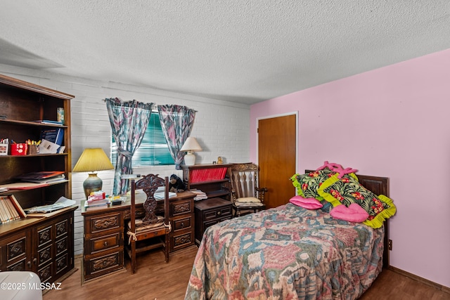 bedroom with a textured ceiling and wood finished floors