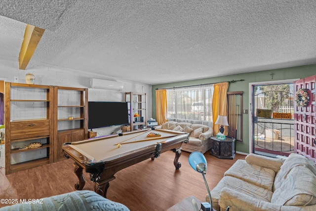 recreation room with a textured ceiling, wood finished floors, billiards, and a wall unit AC