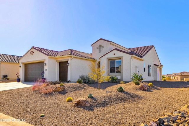 mediterranean / spanish-style home featuring a tiled roof, a garage, driveway, and stucco siding