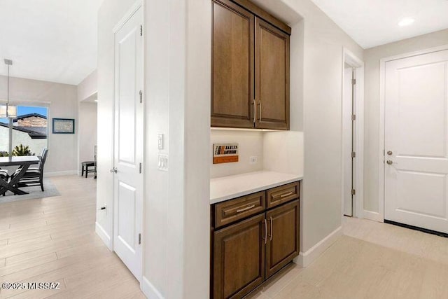 hall featuring light wood finished floors, recessed lighting, and baseboards