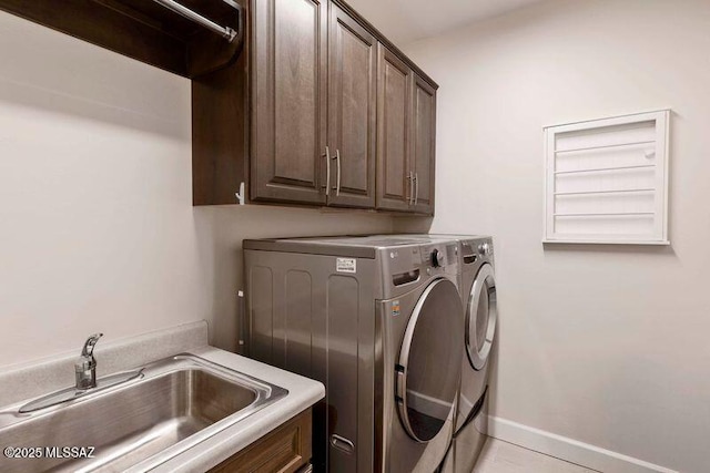 washroom featuring washing machine and clothes dryer, cabinet space, baseboards, and a sink