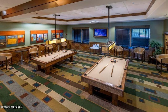 playroom featuring wainscoting, a dry bar, a raised ceiling, and wood walls