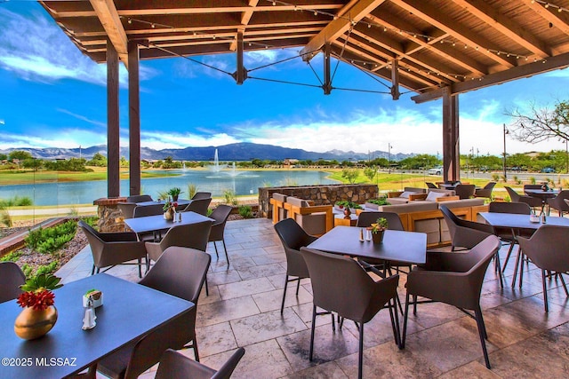 view of patio with a water and mountain view and outdoor dining space