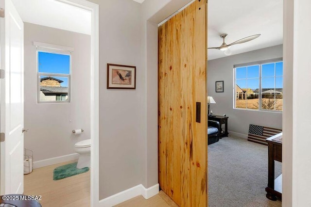 hall featuring light carpet and baseboards