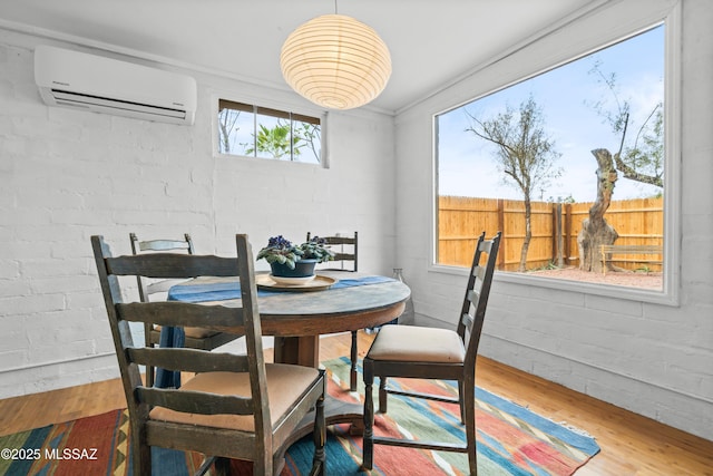 dining space featuring a wall mounted AC and wood finished floors