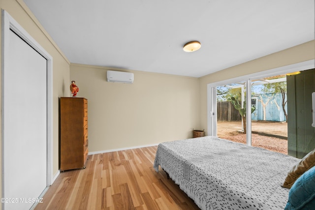 bedroom with a wall mounted air conditioner, baseboards, access to outside, and light wood finished floors