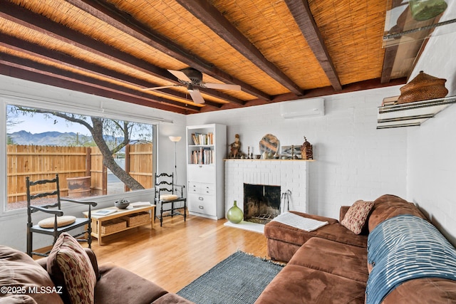 living area with wood finished floors, a wall mounted AC, beam ceiling, wooden ceiling, and a brick fireplace