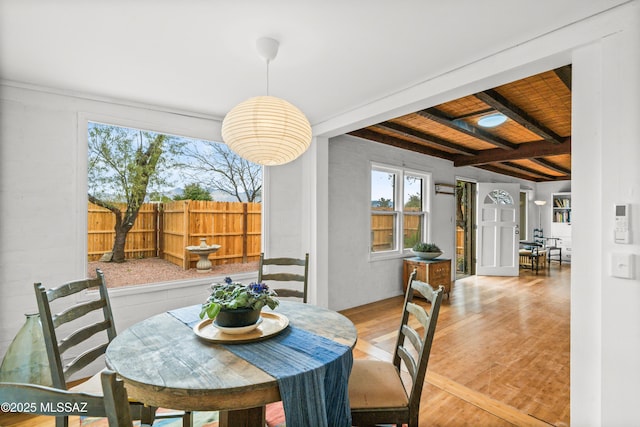 dining area featuring beam ceiling and wood finished floors