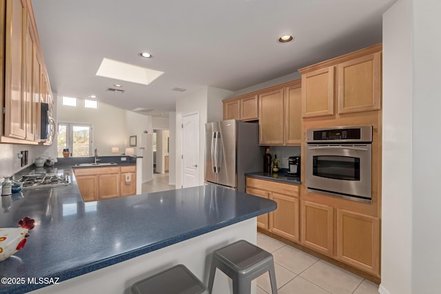 13827 E Fiery Dawn Dr, Vail, AZ 85641 - kitchen with appliances with stainless steel finishes, a skylight, a peninsula, dark countertops, and a kitchen breakfast bar