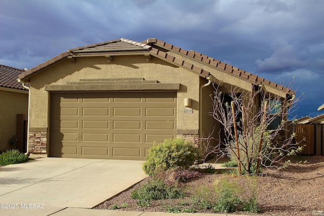 view of front facade featuring stucco siding, a tile roof, stone siding, concrete driveway, and an attached garage