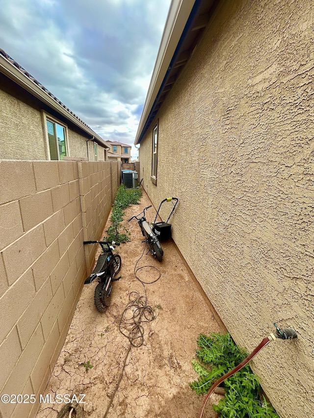 view of property exterior featuring a patio, central air condition unit, a fenced backyard, and stucco siding