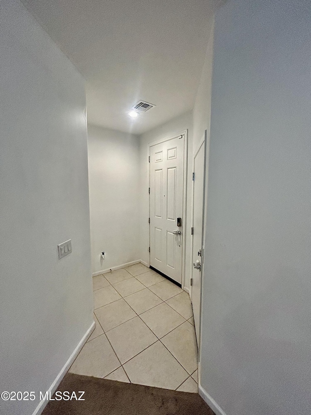 hallway with visible vents, baseboards, and light tile patterned flooring