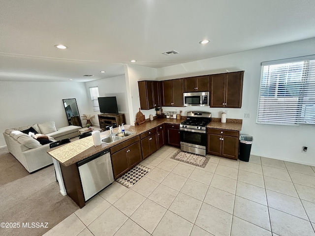 kitchen with visible vents, a sink, dark brown cabinetry, appliances with stainless steel finishes, and open floor plan