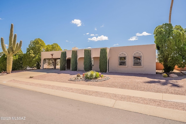 pueblo revival-style home with stucco siding and driveway