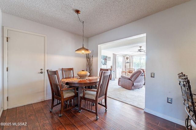 dining space with a textured ceiling, baseboards, and hardwood / wood-style flooring