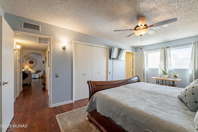 bedroom with a closet, visible vents, arched walkways, and hardwood / wood-style flooring