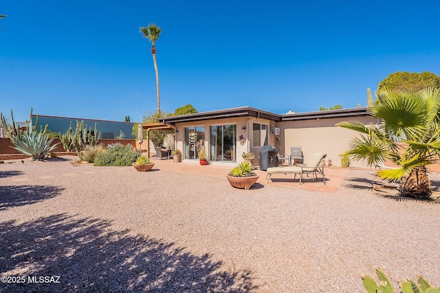 rear view of house with stucco siding and a patio